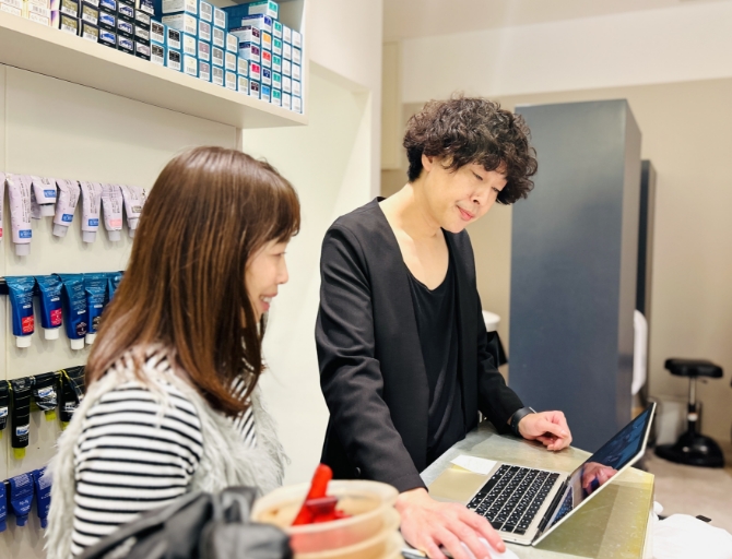 美容室でプロの美容師がお客様の長い髪を丁寧にカットしている様子