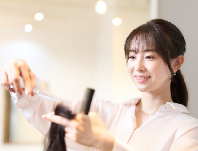 美容室でプロの技術でハサミと髪を持つ笑顔の女性美容師の様子